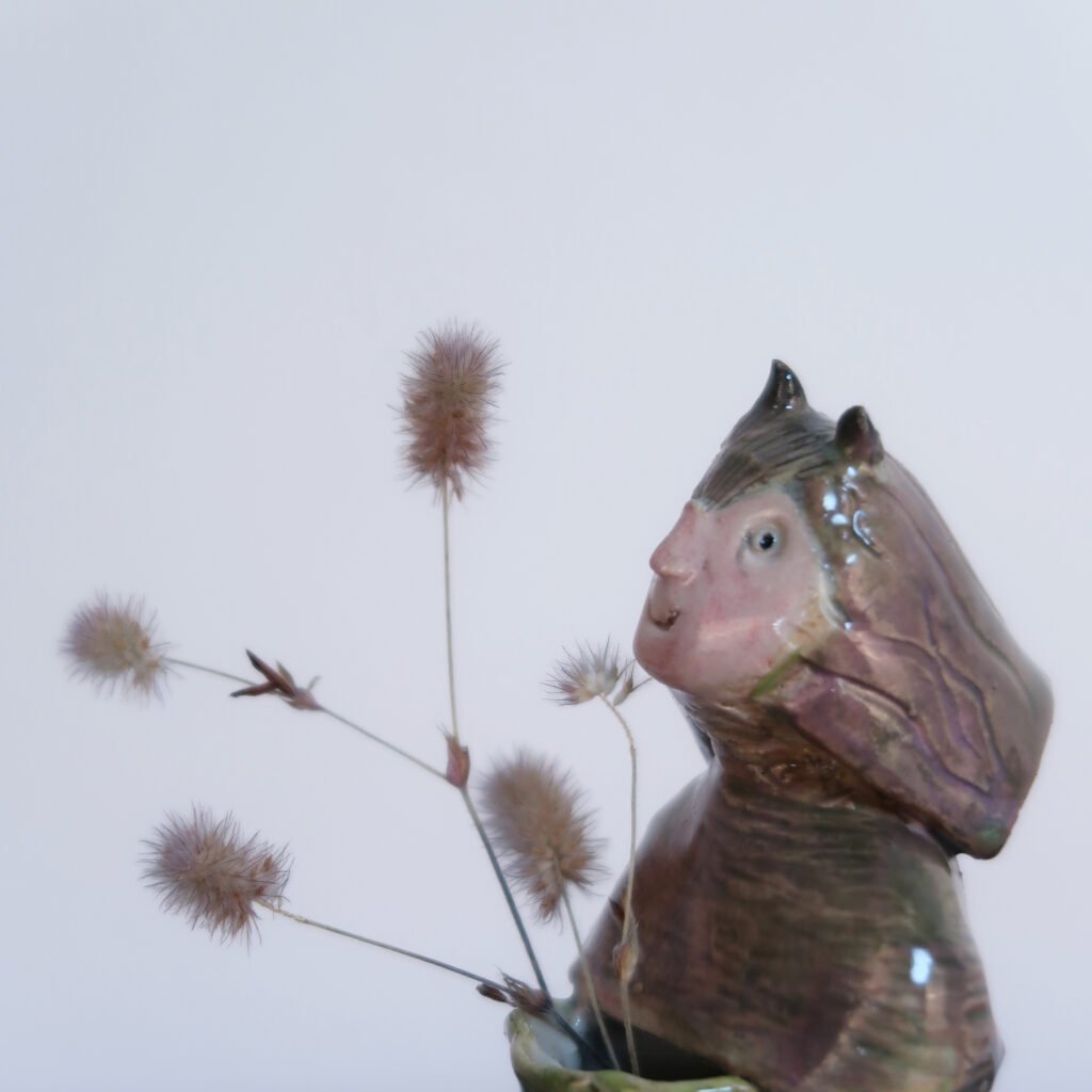 small handmade ceramic bud vase with a sculpted figure
