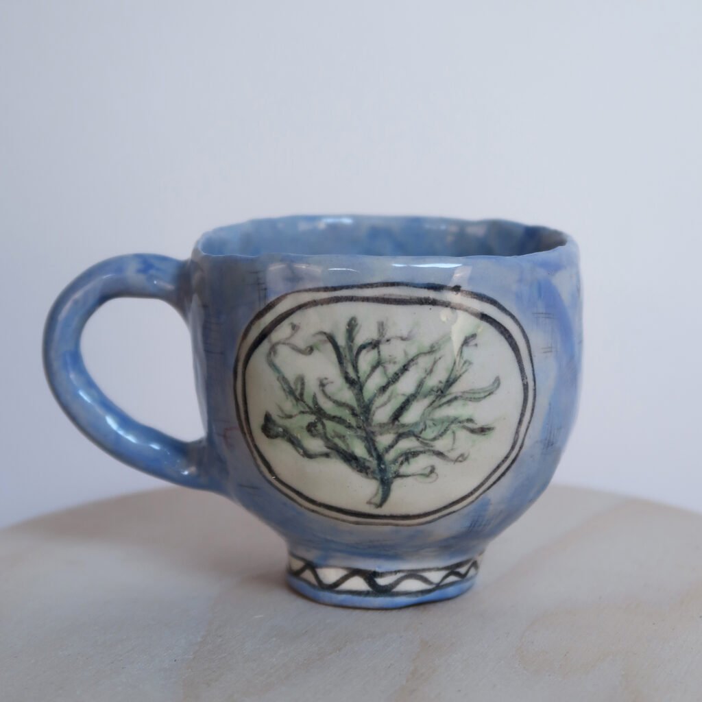 pinched ceramic mug with an illustration of a lichen