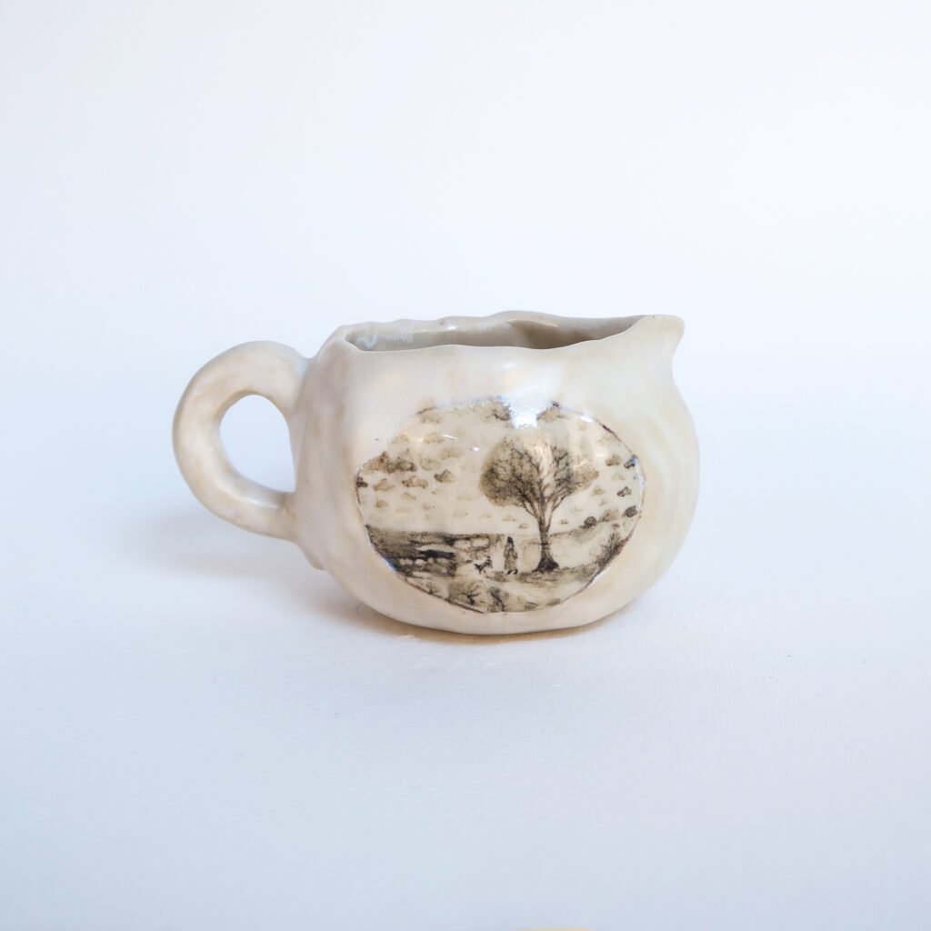 handbuilt ceramic cream jug with a detailed underglaze painting of a scene