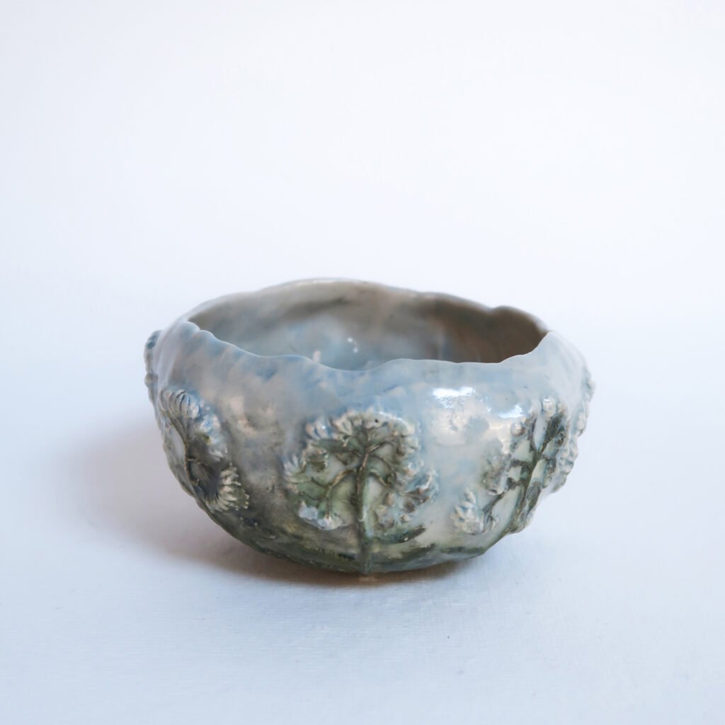 an organically shaped handbuilt ceramic bowl with bar-reliefs of yarrow flowers