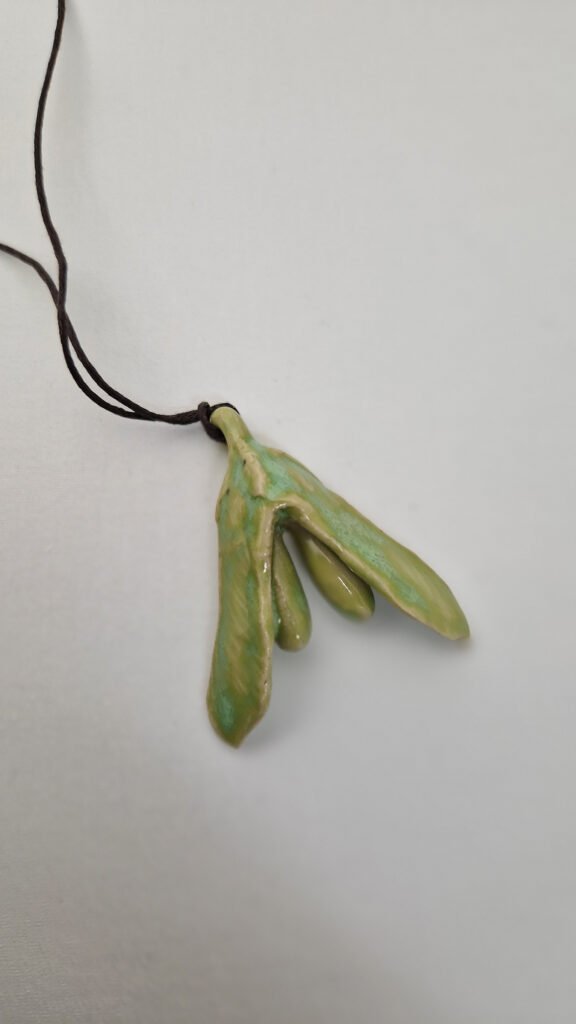 a ceramic pendant that is a hybrid between a maple seed and a clitoris