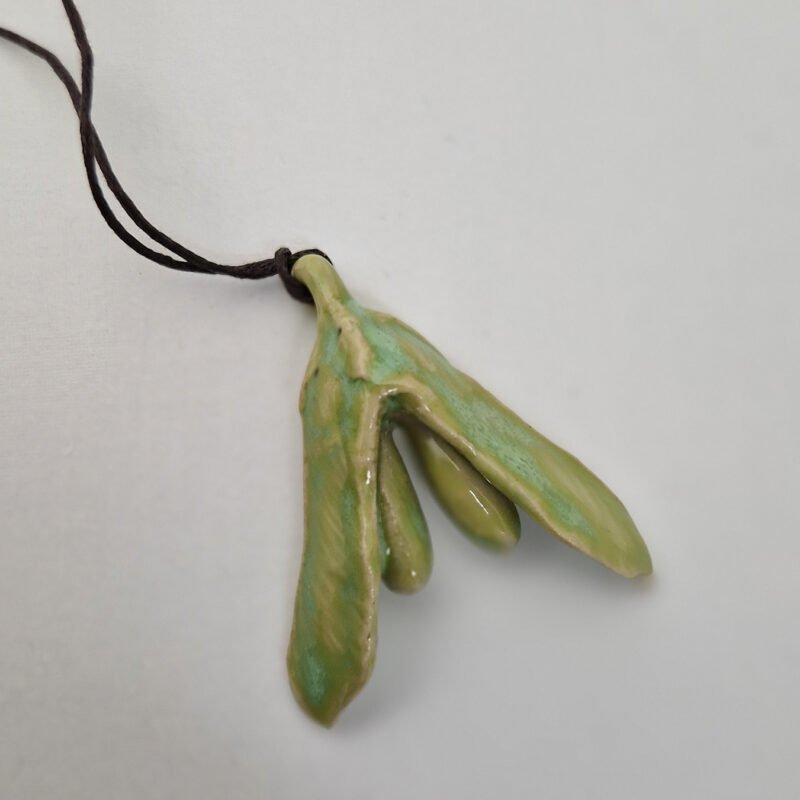 a ceramic pendant that is a hybrid between a maple seed and a clitoris