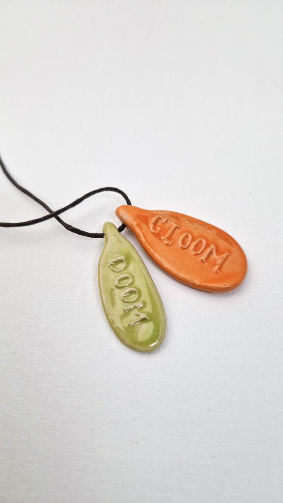 two ceramic pendants with the words doom and gloom