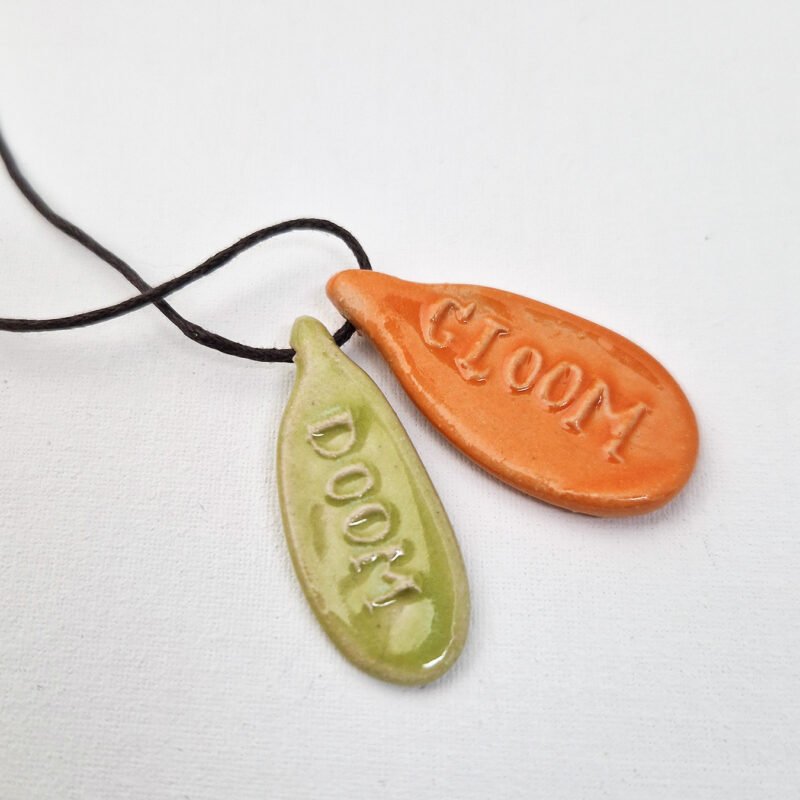 two ceramic pendants with the words doom and gloom