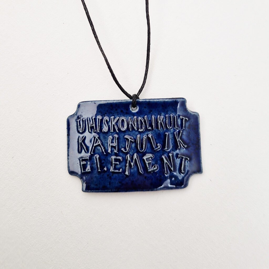 blue ceramic pendant with the words ühiskondlikult kahjulik element