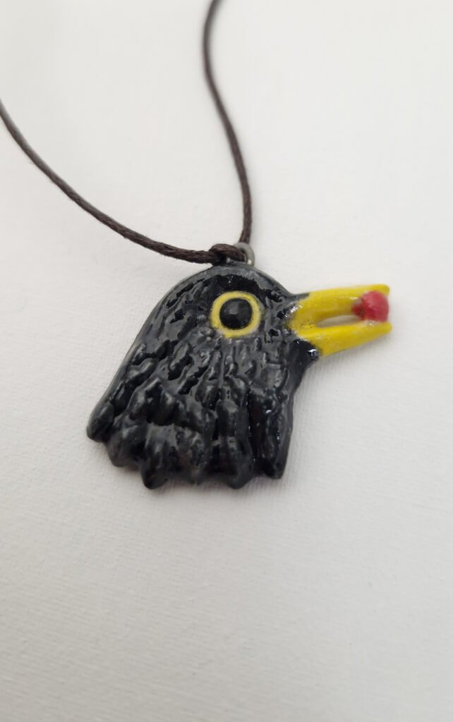 ceramic pendant depicting a blackbird with a red berry in its beak