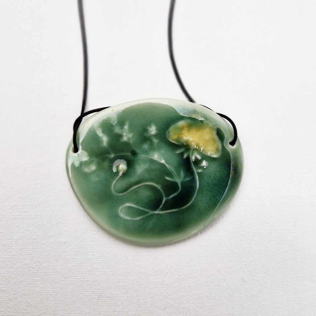 close-up of a ceramic pendant with a buttercup relief