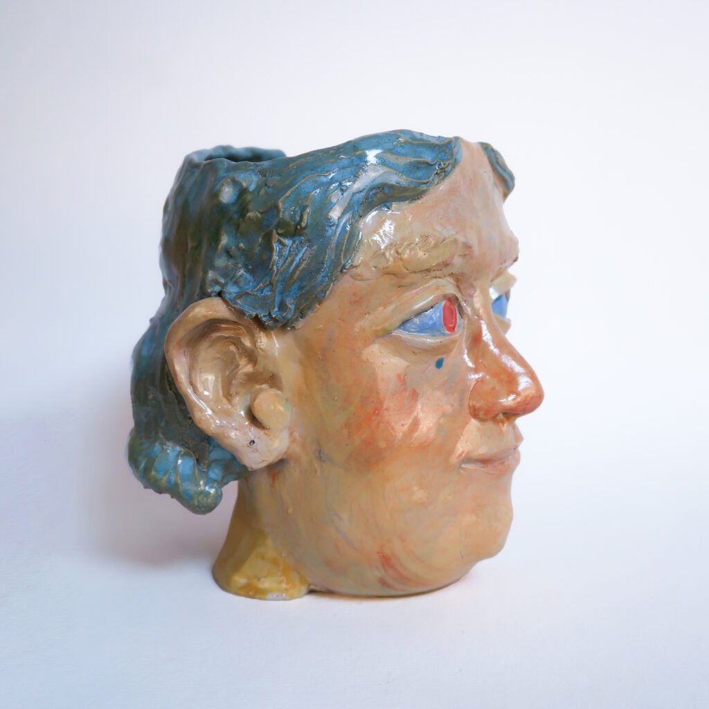 large head-shaped ceramic planter with blue hair and misplaced pupils