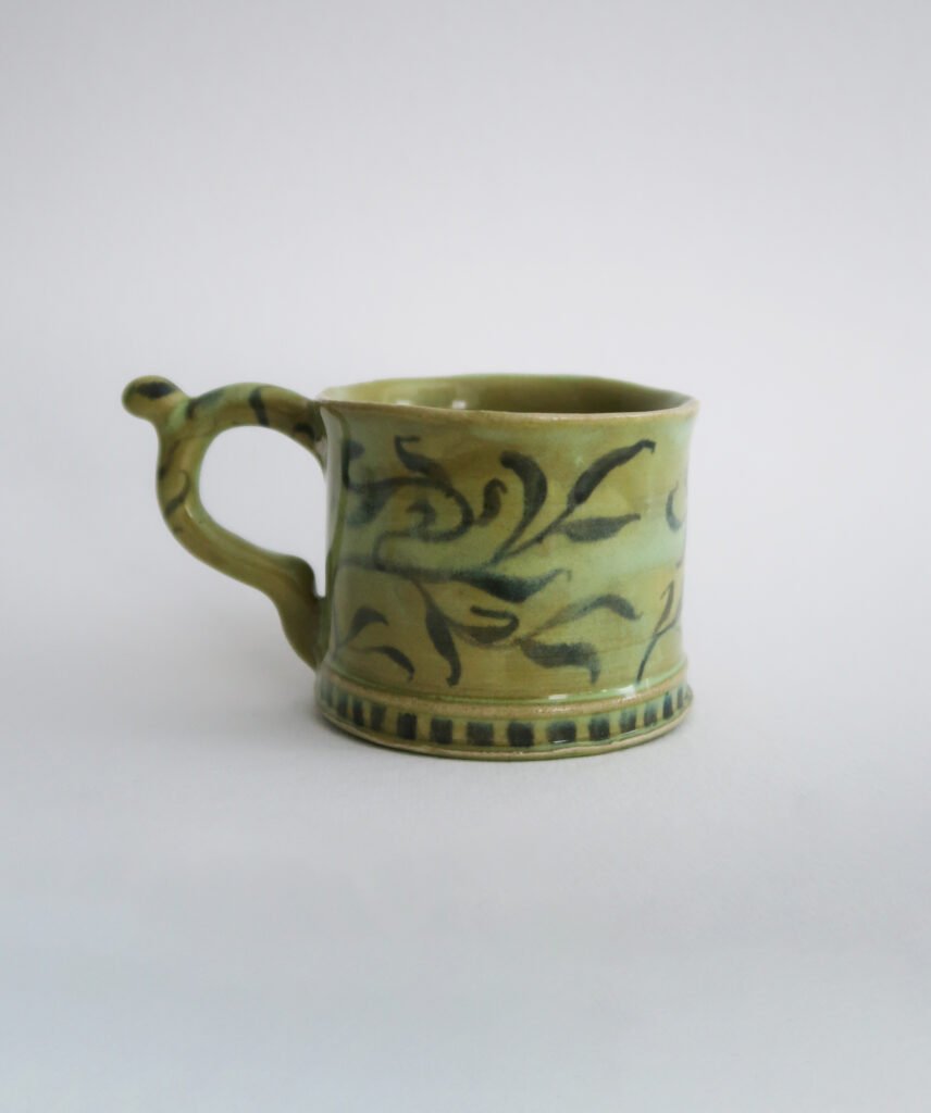 photo of a green handmade ceramic mug with a willow pattern