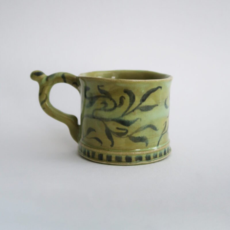 photo of a green handmade ceramic mug with a willow pattern