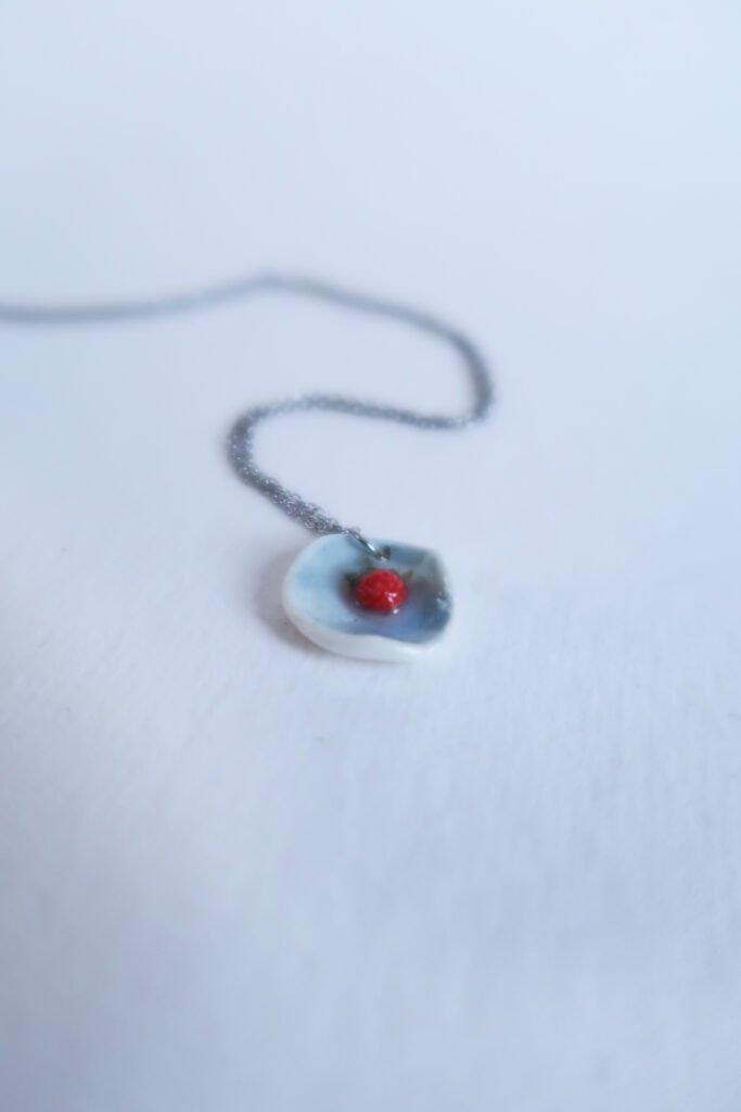 photo of a porcelain pendant with a tiny wild strawberry