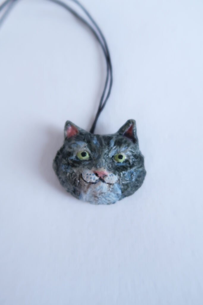 photo of a ceramic pendant depicting the head of a tuxedo cat