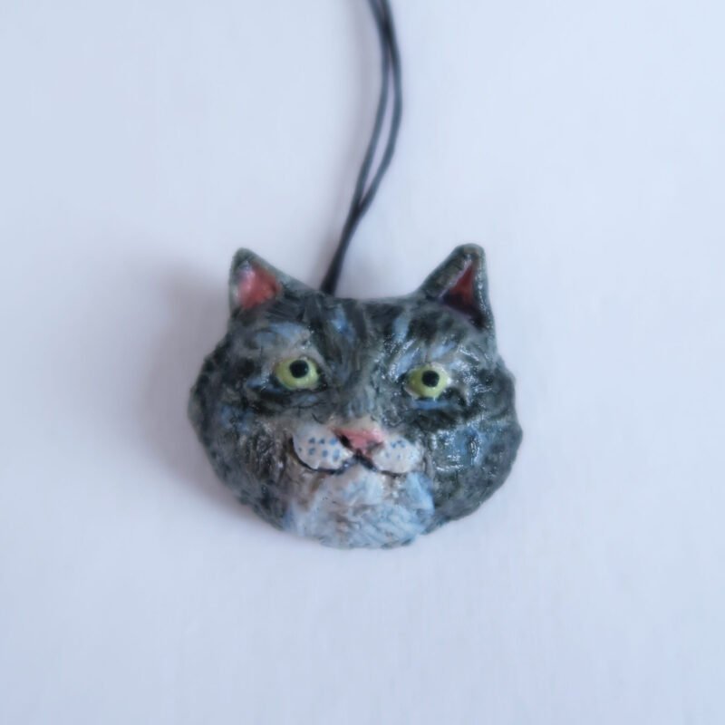photo of a ceramic pendant depicting the head of a tuxedo cat