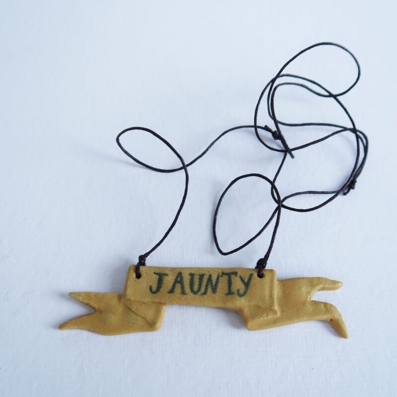ceramic pendant in the shape of a tattered flag, with the word "jaunty"