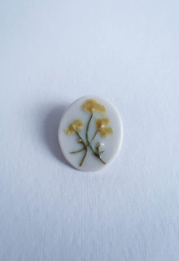 photo of a porcelain brooch with a buttercup relief