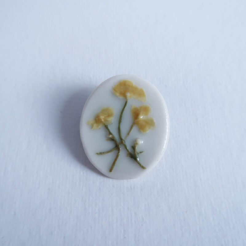 photo of a porcelain brooch with a buttercup relief
