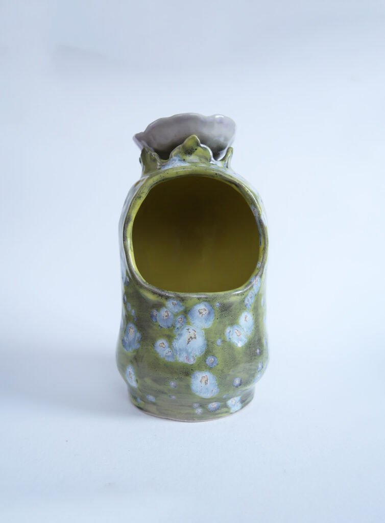photo of a tall curvy ceramic salt cellar glazed with something akin to space vomit.