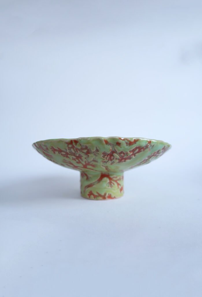 green ceramic footed bowl with a red lichen pattern