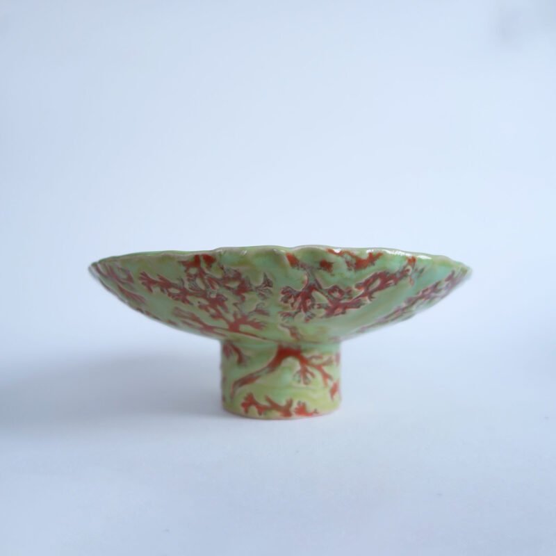 green ceramic footed bowl with a red lichen pattern