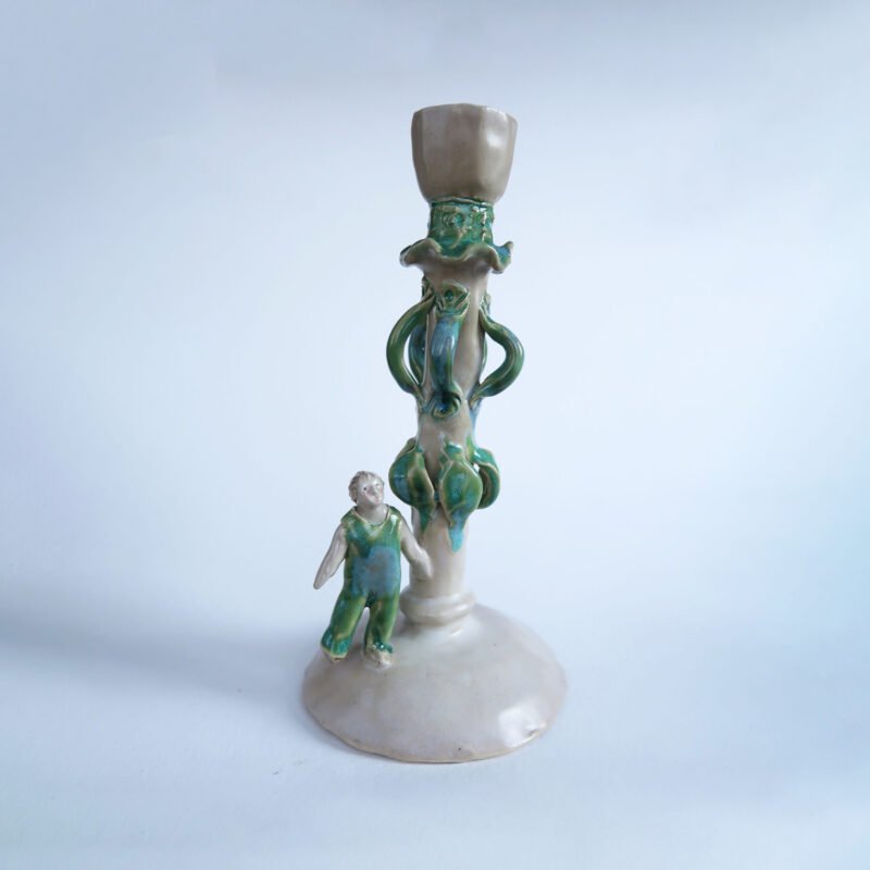 photo of a handmade ceramic candlestick wth a tiny figure wearing overalls
