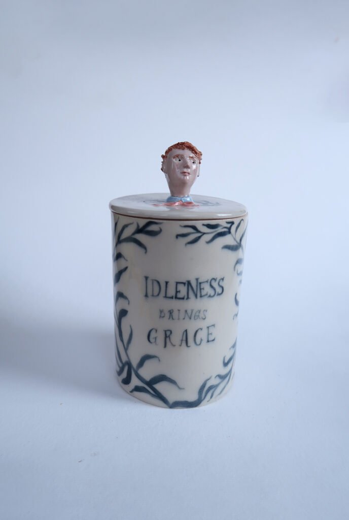 photo of a handmade ceramic jar with a hand-painted a willow pattern and a dandy topper
