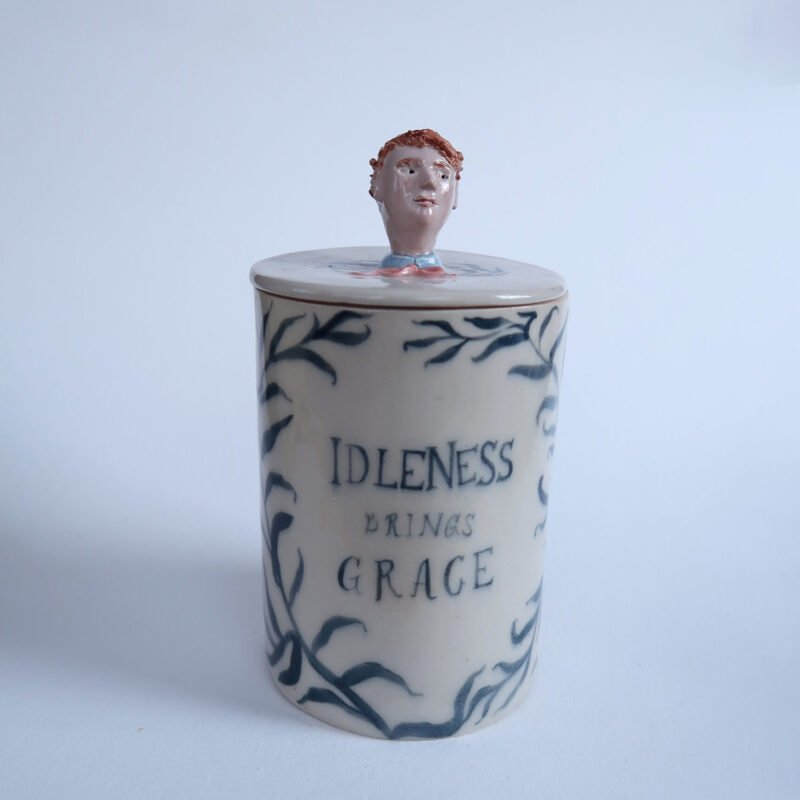 photo of a handmade ceramic jar with a hand-painted a willow pattern and a dandy topper