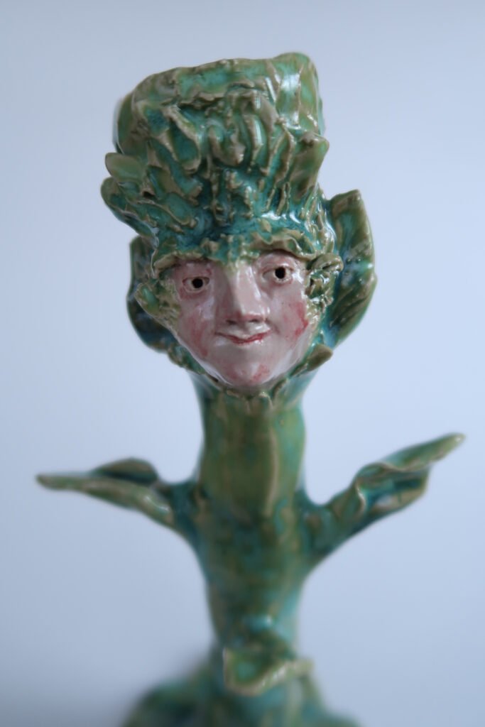 photo of a handmade ceramic candlestick in the shape of a plant and a benevolent face