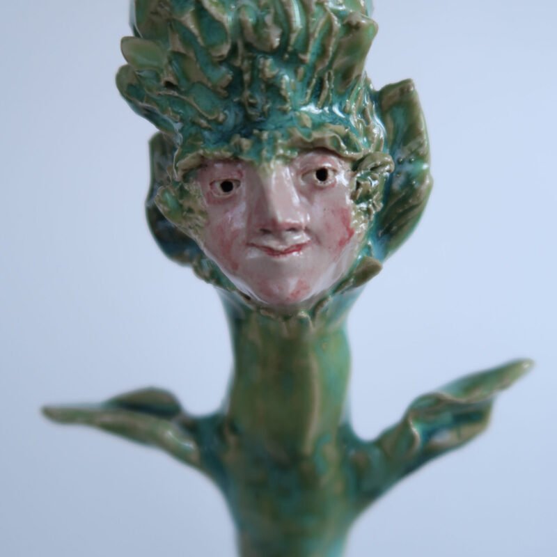 photo of a handmade ceramic candlestick in the shape of a plant and a benevolent face